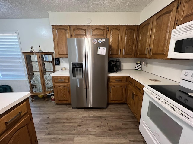 kitchen with a textured ceiling, dark hardwood / wood-style flooring, and white appliances