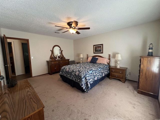 bedroom featuring light carpet, ceiling fan, and a textured ceiling