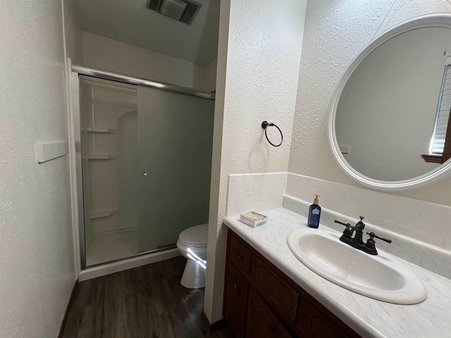 bathroom with vanity, an enclosed shower, tasteful backsplash, wood-type flooring, and toilet