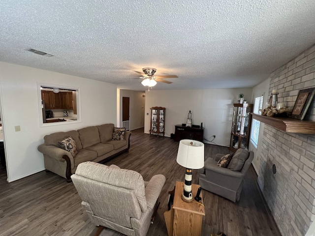 living room with a fireplace, ceiling fan, dark wood-type flooring, and a textured ceiling