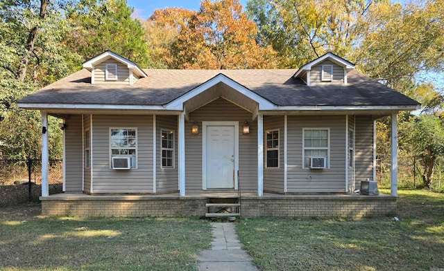 bungalow-style home featuring a porch, cooling unit, and a front yard