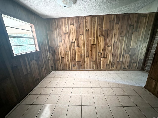 tiled empty room with wooden walls and a textured ceiling