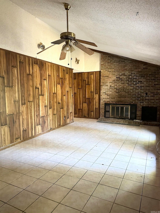 unfurnished living room with vaulted ceiling, wooden walls, and a textured ceiling