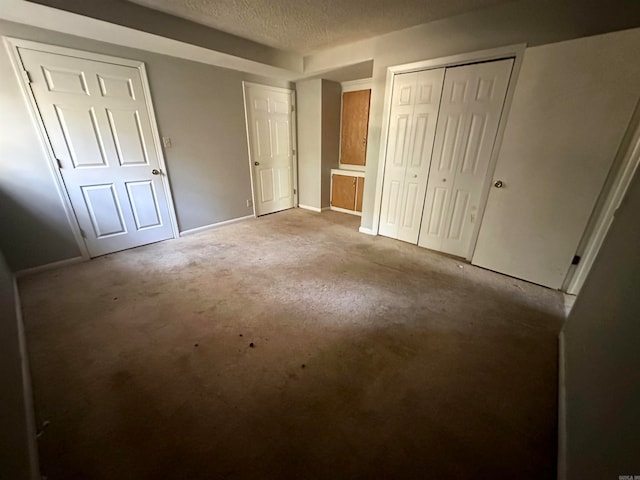 unfurnished bedroom featuring two closets, carpet, and a textured ceiling