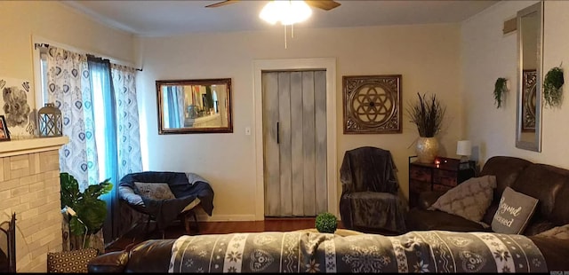 living room featuring ceiling fan, a fireplace, and dark wood-type flooring