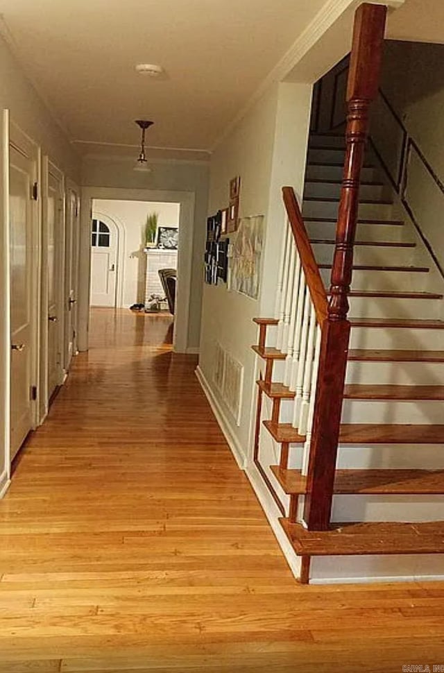 hall with ornamental molding and light wood-type flooring