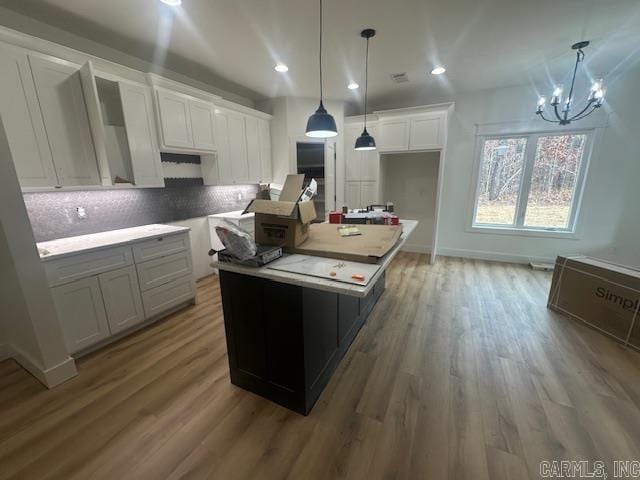 kitchen with white cabinets, pendant lighting, a center island, and backsplash