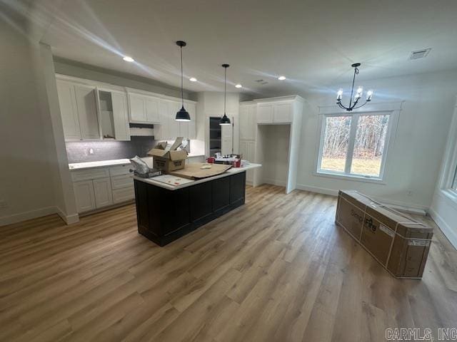 kitchen featuring pendant lighting, white cabinetry, a kitchen island, and light hardwood / wood-style floors