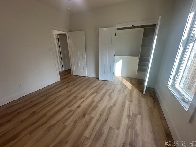 unfurnished bedroom with light wood-type flooring and a closet