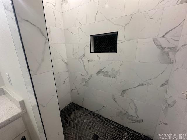 bathroom featuring a tile shower and vanity