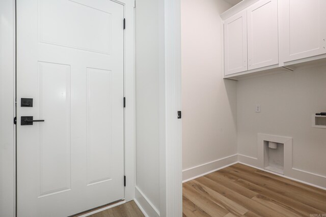 clothes washing area featuring cabinets, hookup for a washing machine, light hardwood / wood-style floors, and hookup for an electric dryer