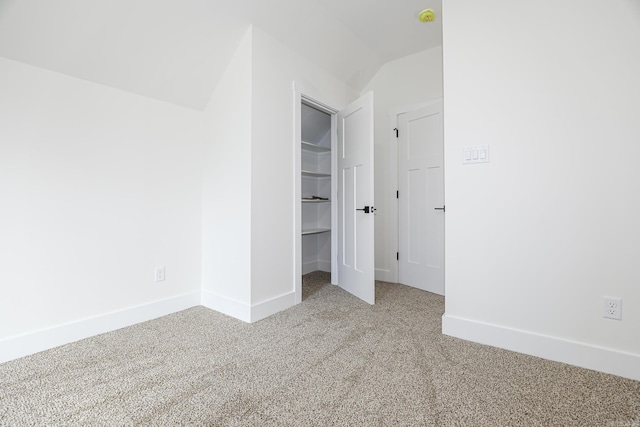 unfurnished bedroom with a closet, carpet floors, and vaulted ceiling