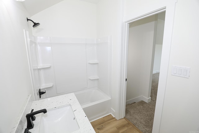 bathroom with hardwood / wood-style flooring, shower / bath combination, and sink