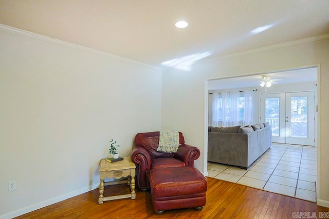 sitting room with french doors, light wood-type flooring, ornamental molding, and ceiling fan