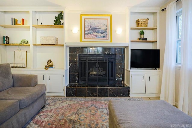 living room featuring a fireplace, built in features, and crown molding