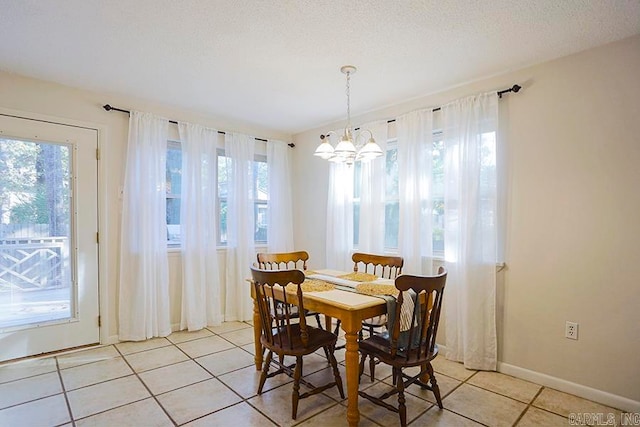 tiled dining space with a notable chandelier, a textured ceiling, and a healthy amount of sunlight