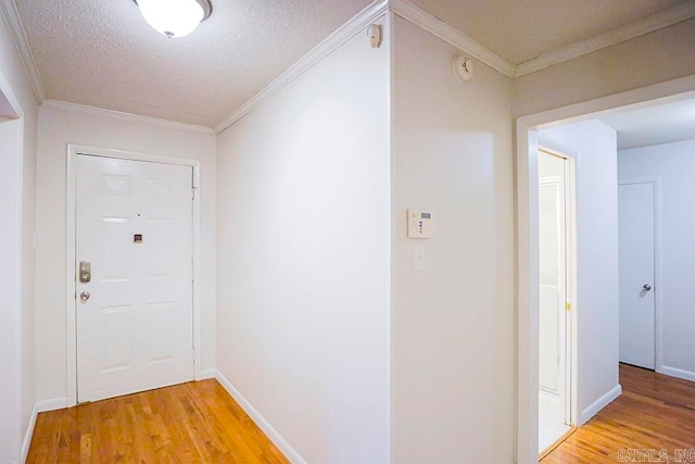 hallway with a textured ceiling, ornamental molding, and light hardwood / wood-style flooring