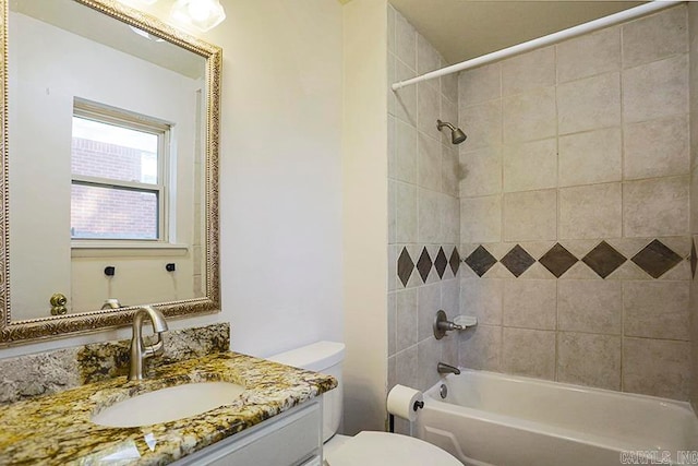 full bathroom with tiled shower / bath, vanity, and toilet