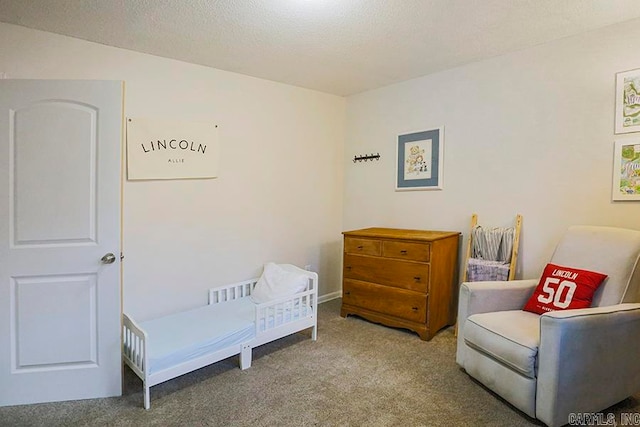 bedroom with a crib, carpet, and a textured ceiling