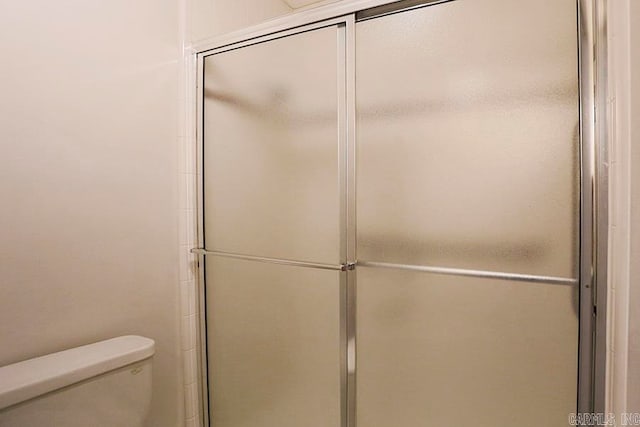 bathroom with a shower with door and toilet