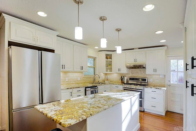 kitchen with white cabinets, appliances with stainless steel finishes, a wealth of natural light, and decorative light fixtures