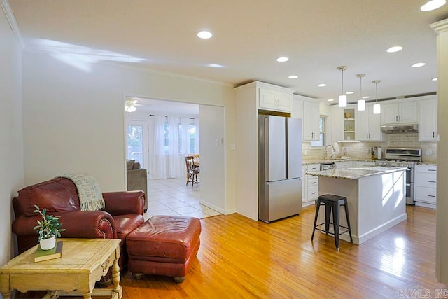 kitchen with appliances with stainless steel finishes, pendant lighting, white cabinetry, and light wood-type flooring