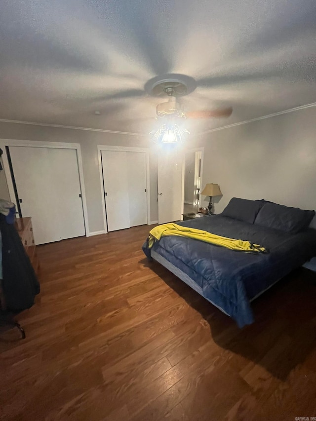 bedroom with hardwood / wood-style floors, multiple closets, and ceiling fan