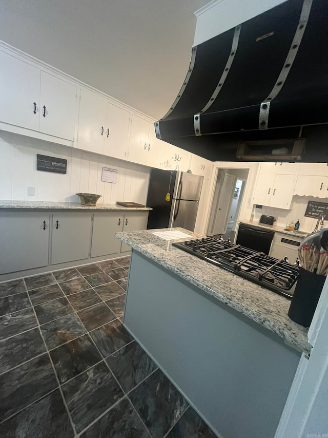 kitchen with light stone counters, exhaust hood, stainless steel fridge, white cabinetry, and backsplash