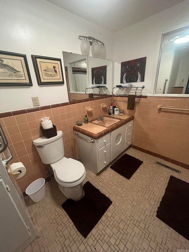 bathroom featuring vanity, tile walls, tile patterned flooring, and toilet