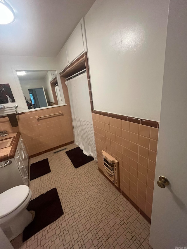 bathroom with tile patterned flooring, walk in shower, toilet, tile walls, and vanity