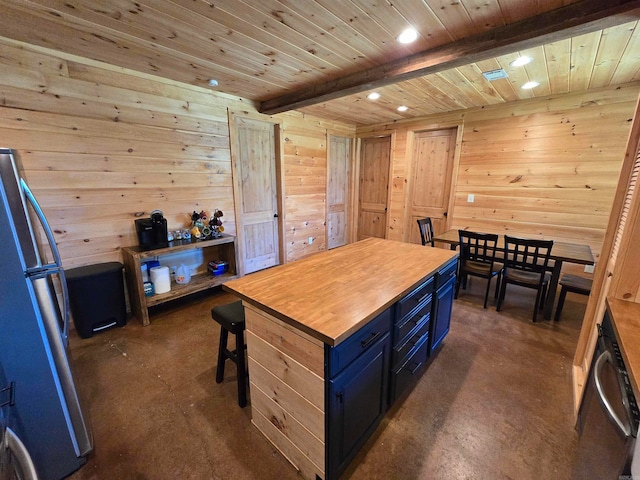 kitchen featuring a kitchen island, wooden walls, stainless steel appliances, blue cabinetry, and beam ceiling