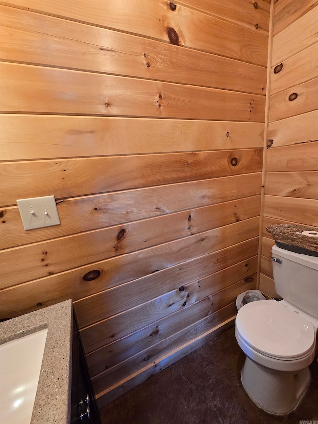 bathroom featuring wooden walls, toilet, and vanity