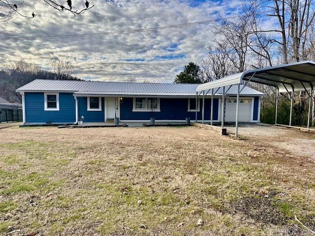 ranch-style house featuring a carport, a porch, a garage, and a front yard