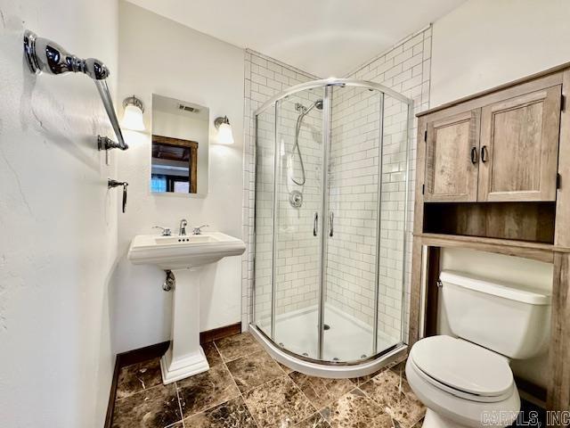 bathroom featuring toilet, an enclosed shower, and sink