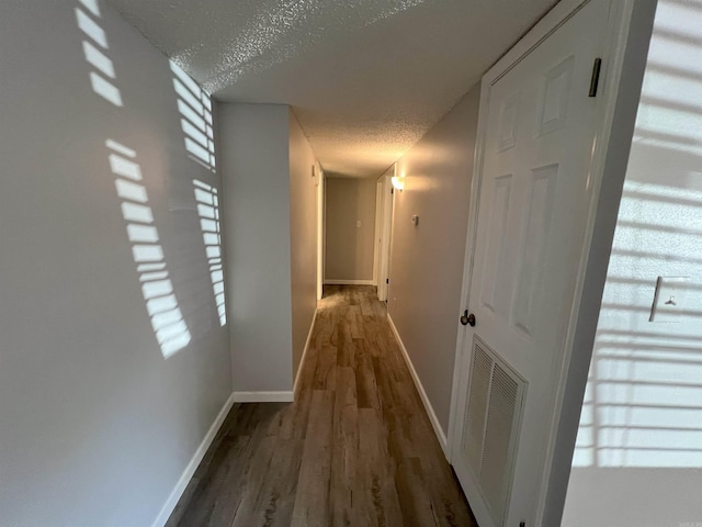 hall with hardwood / wood-style flooring and a textured ceiling