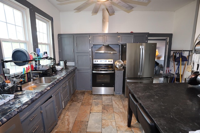 kitchen with ceiling fan, sink, gray cabinets, wall chimney exhaust hood, and stainless steel appliances