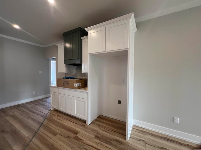 kitchen with crown molding, light wood finished floors, light countertops, white cabinets, and baseboards