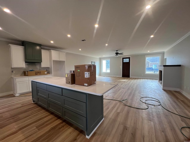 kitchen with light wood finished floors, white cabinets, open floor plan, a center island, and light countertops