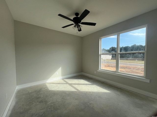 unfurnished room with ceiling fan, baseboards, and concrete flooring