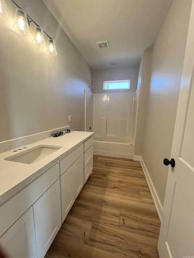 bathroom with baseboards, visible vents, wood finished floors, vanity, and shower / washtub combination