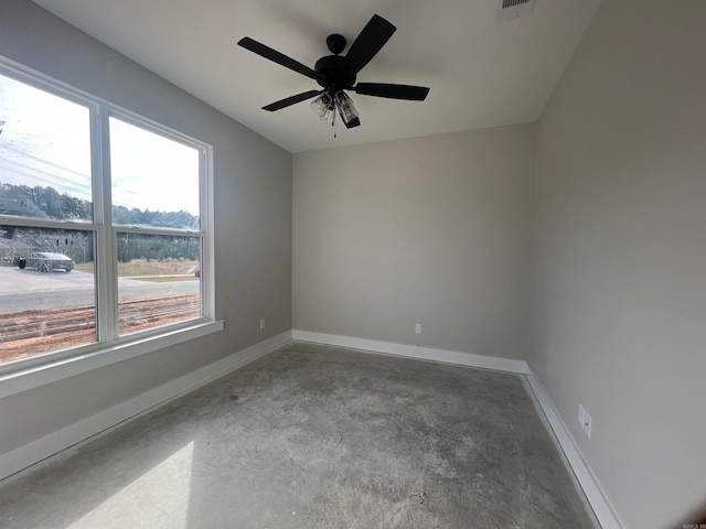 spare room with ceiling fan, visible vents, baseboards, and unfinished concrete flooring