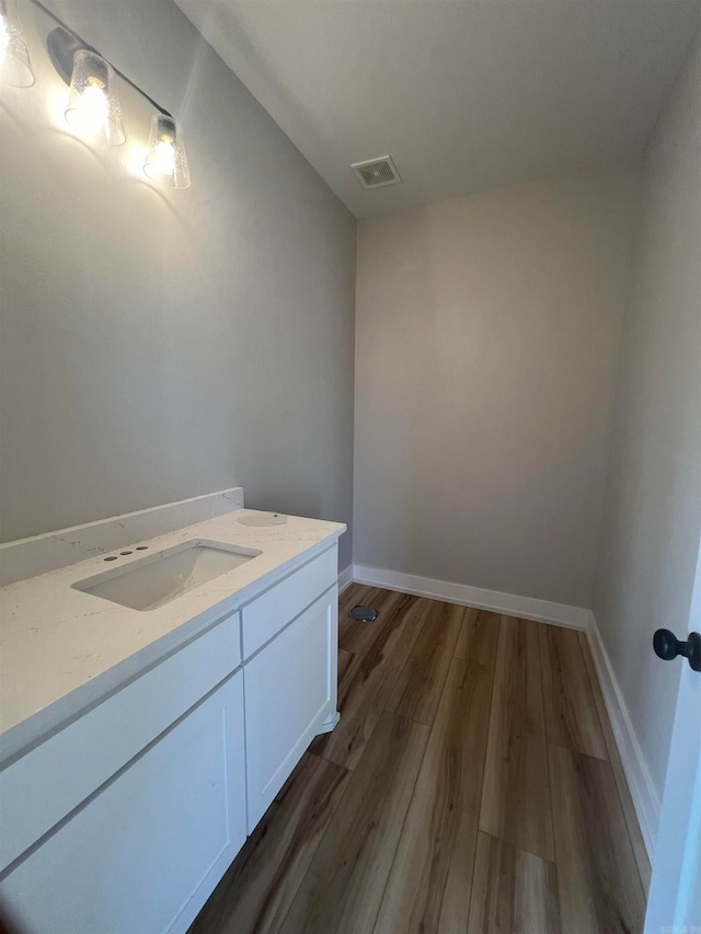 bathroom with visible vents, vanity, baseboards, and wood finished floors