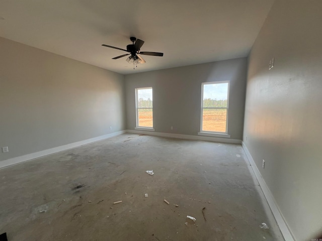 spare room with concrete floors, a ceiling fan, and baseboards