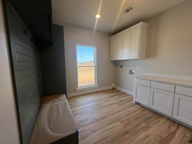 washroom with hookup for an electric dryer, washer hookup, visible vents, cabinet space, and light wood finished floors