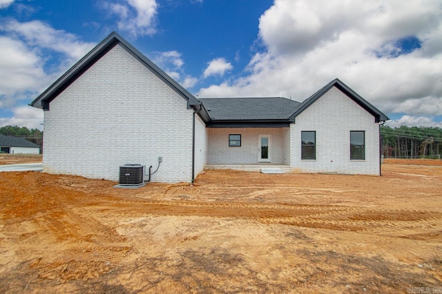 rear view of property featuring brick siding and central AC