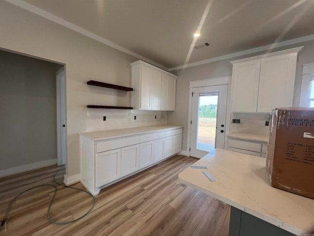 kitchen featuring ornamental molding, light wood-type flooring, white cabinets, and visible vents