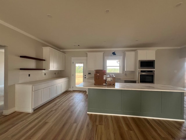 kitchen with oven, white cabinets, light countertops, a large island, and built in microwave