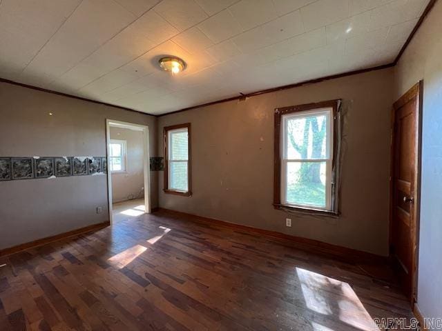 empty room featuring crown molding, plenty of natural light, and dark hardwood / wood-style flooring