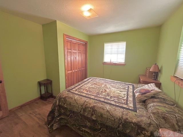 bedroom with a closet, hardwood / wood-style floors, and a textured ceiling