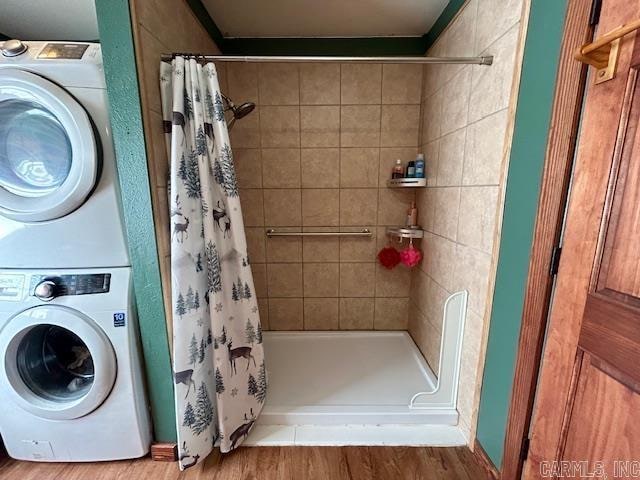 laundry room featuring wood-type flooring and stacked washing maching and dryer